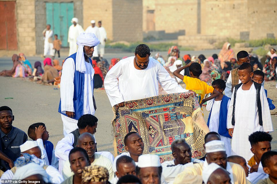 السودان: رجال يرتدون ملابس دينية ورجل يحمل سجادة صلاة يجتمعون للصلاة في بورتسودان ، السودان ، يوم الجمعة