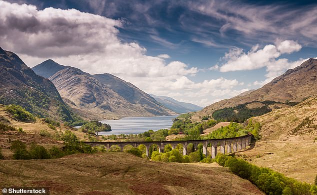 جسر Glenfinnan يحمل خط سكة حديد West Highland عالياً فوق وادي Glenfinnan بجانب البحيرات والجبال في اسكتلندا - تعد المرتفعات وجهة شهيرة أخرى لقضاء العطلات