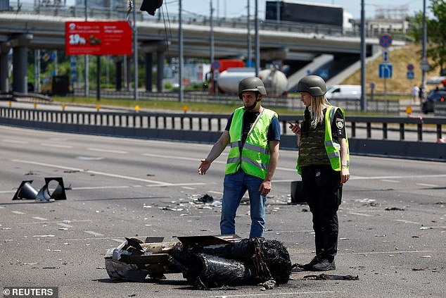 في الصورة: ضباط شرطة يقفون بجوار جزء من صاروخ سقط في شارع خلال غارة روسية في كييف ، في 29 مايو 2023.