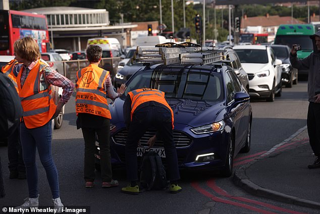 يبدو أن متظاهري Just Stop Oil يطلبون من سائق سيارة التوقف أثناء قيامهم بمسيرة بطيئة في Hanger Lane ، غرب لندن صباح الاثنين