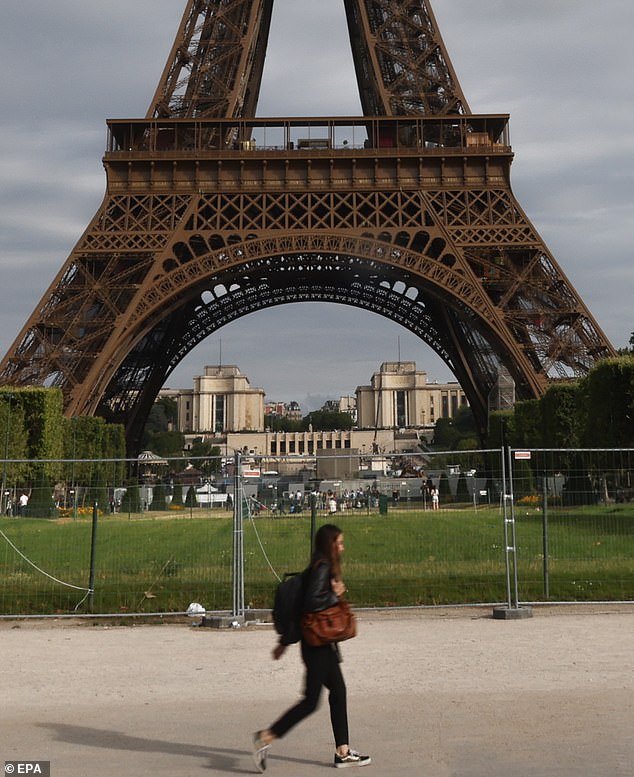 شخص يسير بجوار Champ de Mars وبرج إيفل المحصن في باريس ، فرنسا ، 3 يوليو 2023