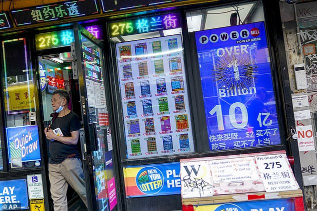 في مدينة نيويورك ، لافتة تعلن عن جائزة Powerball التي تزيد قيمتها عن مليار دولار بينما يغادر رجل المتجر بتذاكر اليانصيب الخاصة به الأربعاء