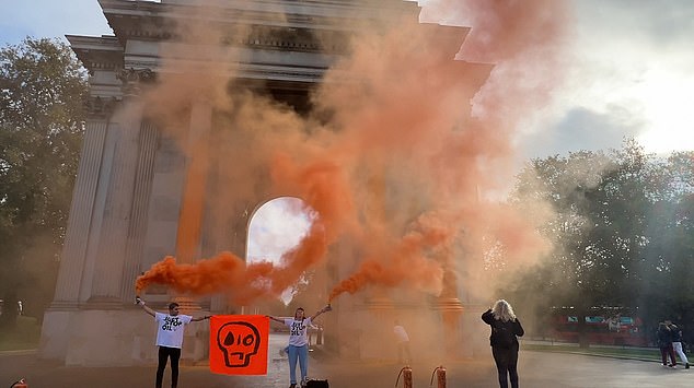 بعد طلاء القوس التاريخي بالطلاء، أشعل الثلاثي مشاعل برتقالية وساعدوا في رفع علامتهم الشهيرة