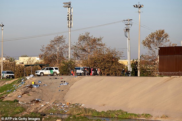 مجموعة من المهاجرين يقفون بجوار شاحنة دورية الحدود بعد استسلامهم في نهر تيخوانا على الحدود بين الولايات المتحدة والمكسيك.