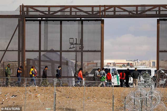 مهاجرون يطلبون اللجوء يسيرون بالقرب من السياج على الحدود بين الولايات المتحدة والمكسيك، في انتظار معالجتها في إل باسو