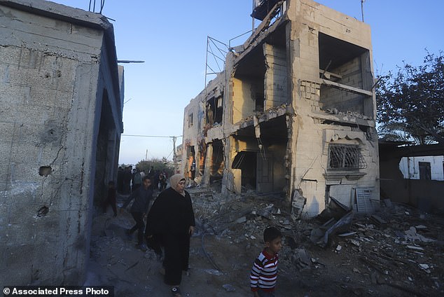 فلسطينيون يسيرون بجوار مبنى سكني دمر في غارة إسرائيلية في رفح بقطاع غزة، الأحد 11 فبراير 2024.