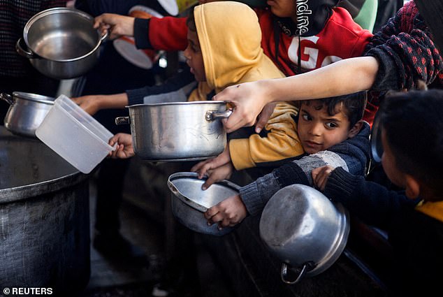 أطفال فلسطينيون ينتظرون الحصول على الطعام المطبوخ في مطبخ خيري وسط نقص الإمدادات الغذائية، في رفح، جنوب قطاع غزة، في 5 مارس/آذار.