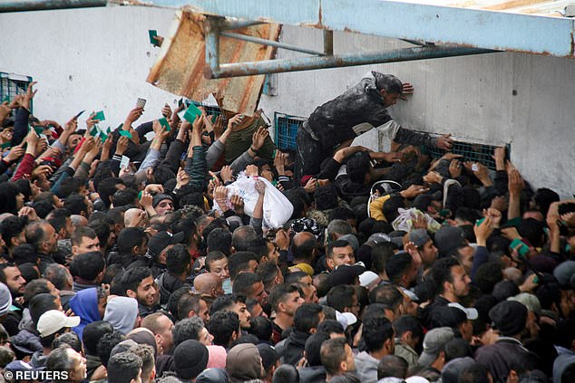 فلسطينيون يتجمعون لتلقي المساعدات خارج مستودع للأونروا بينما يواجه سكان غزة مستويات أزمة الجوع، 18 مارس 2024