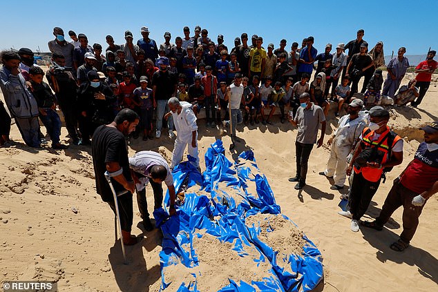 يشاهد الناس جثث فلسطينيين مجهولين يتم دفنها في مقبرة جماعية بعد أن سلمتها إسرائيل، وسط صراع بين إسرائيل وحماس، في خان يونس، جنوب قطاع غزة 5 أغسطس 2024